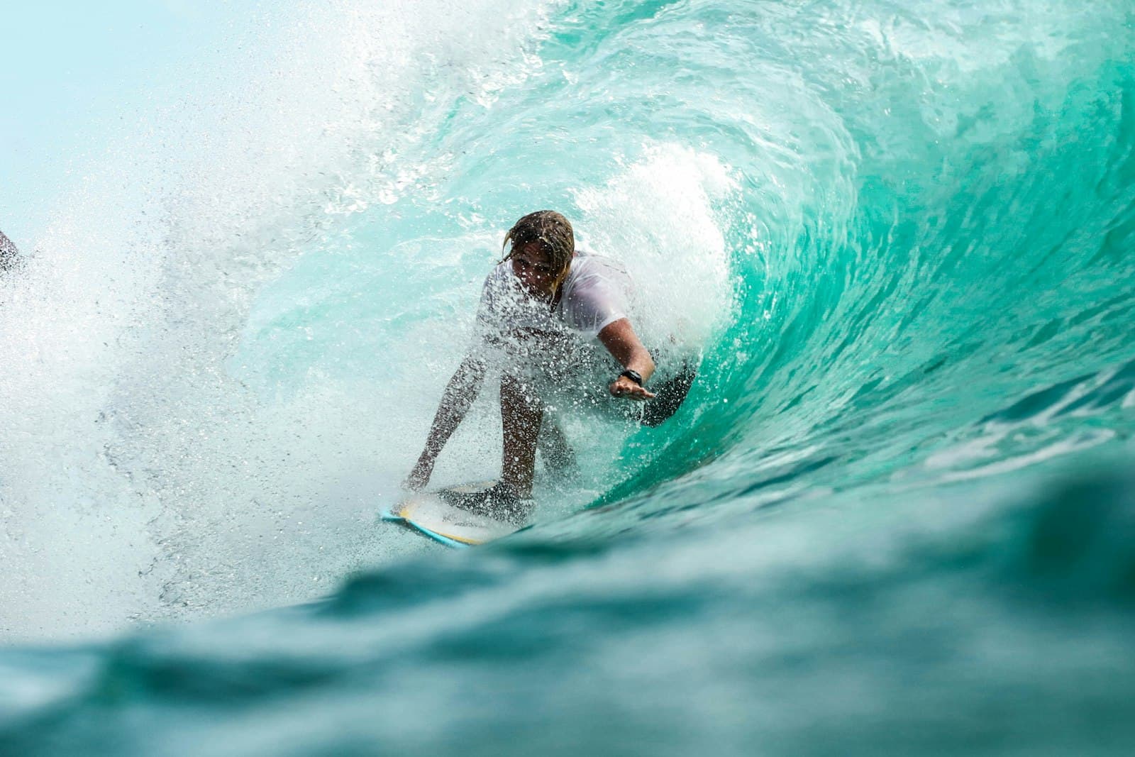 A surfer riding inside the curl of a breaking wave