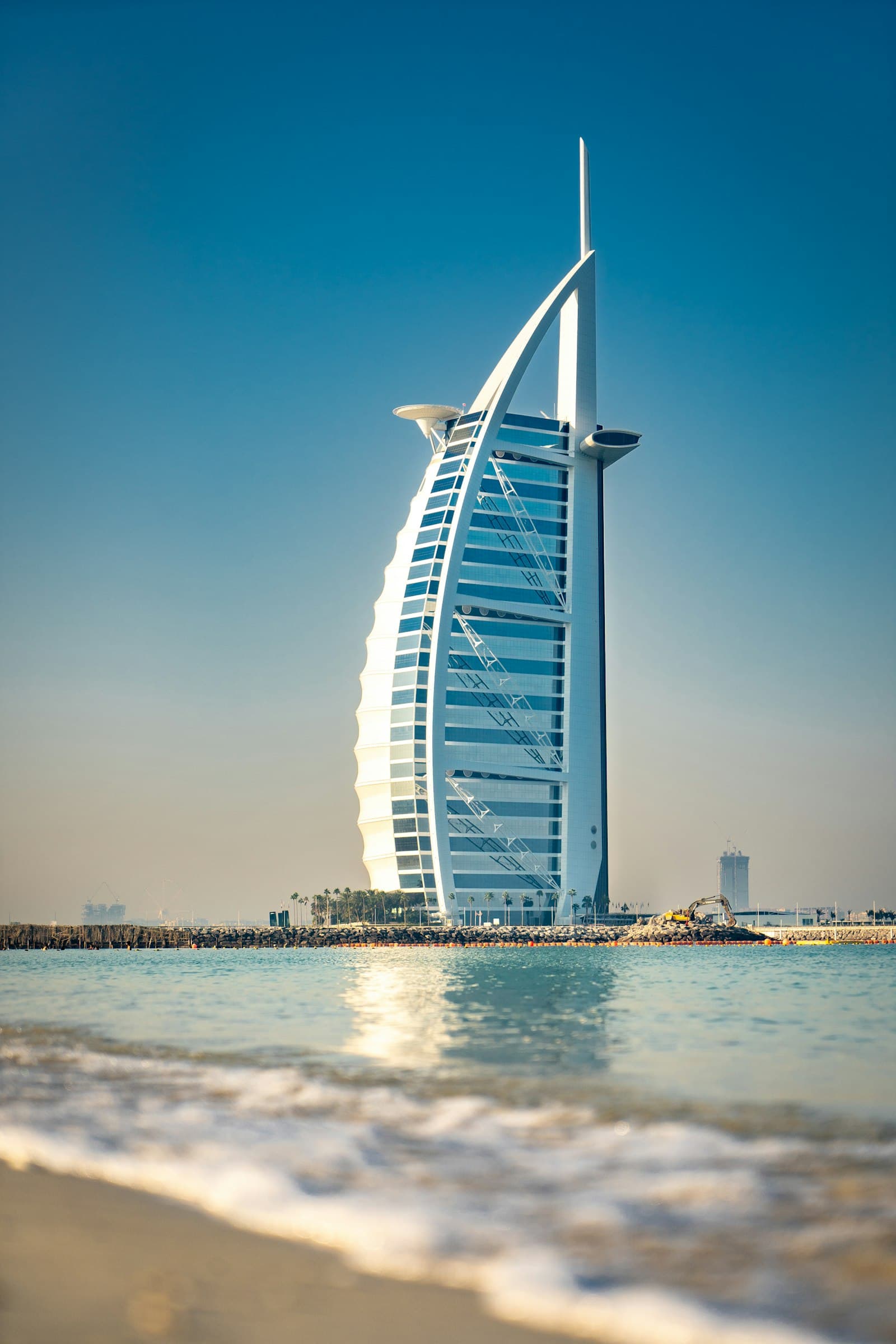 A sail-shaped luxury hotel lit against a deep blue evening sky