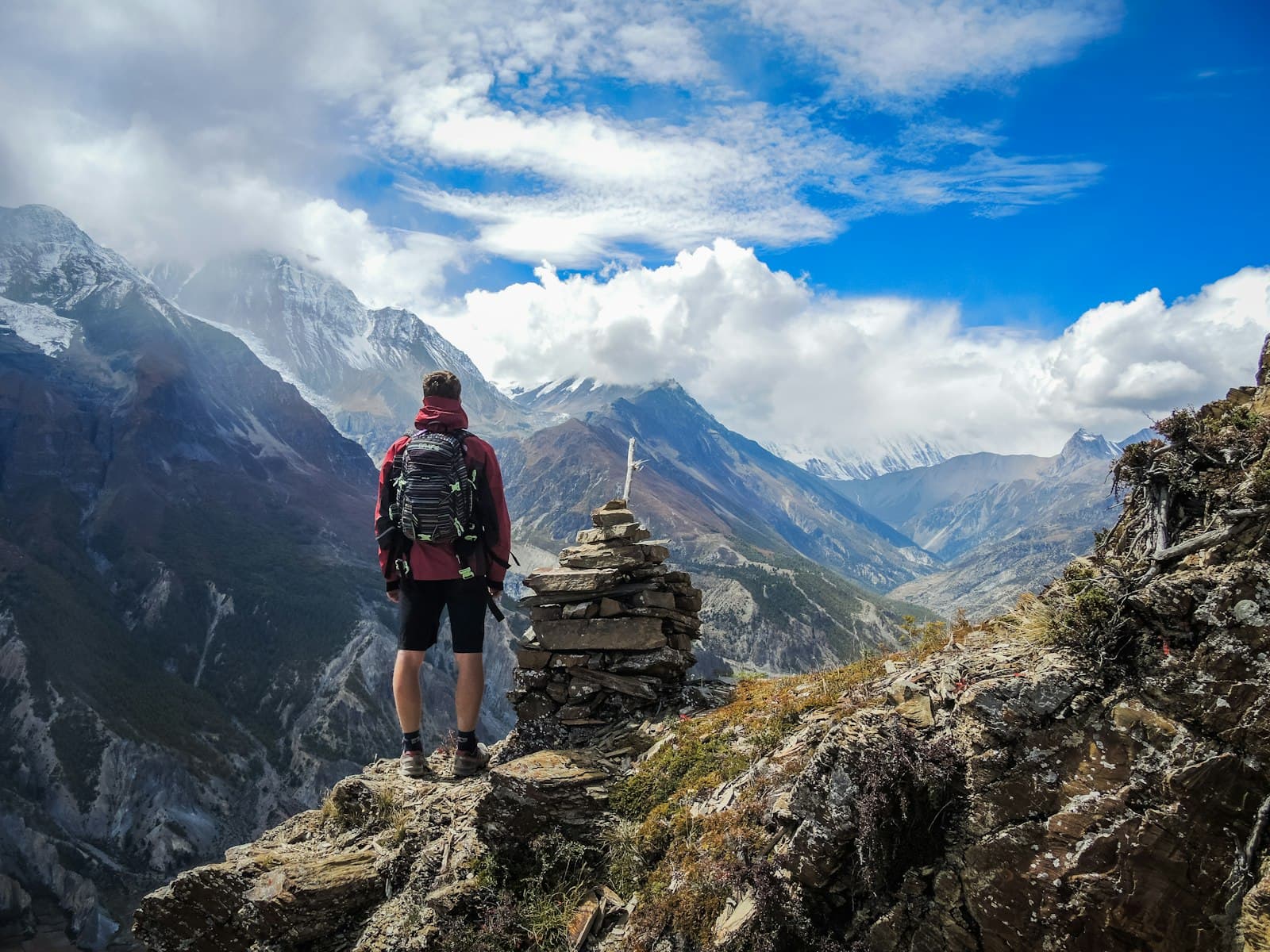 A traveller standing on a rocky outcrop looking across a wide mountain valley
