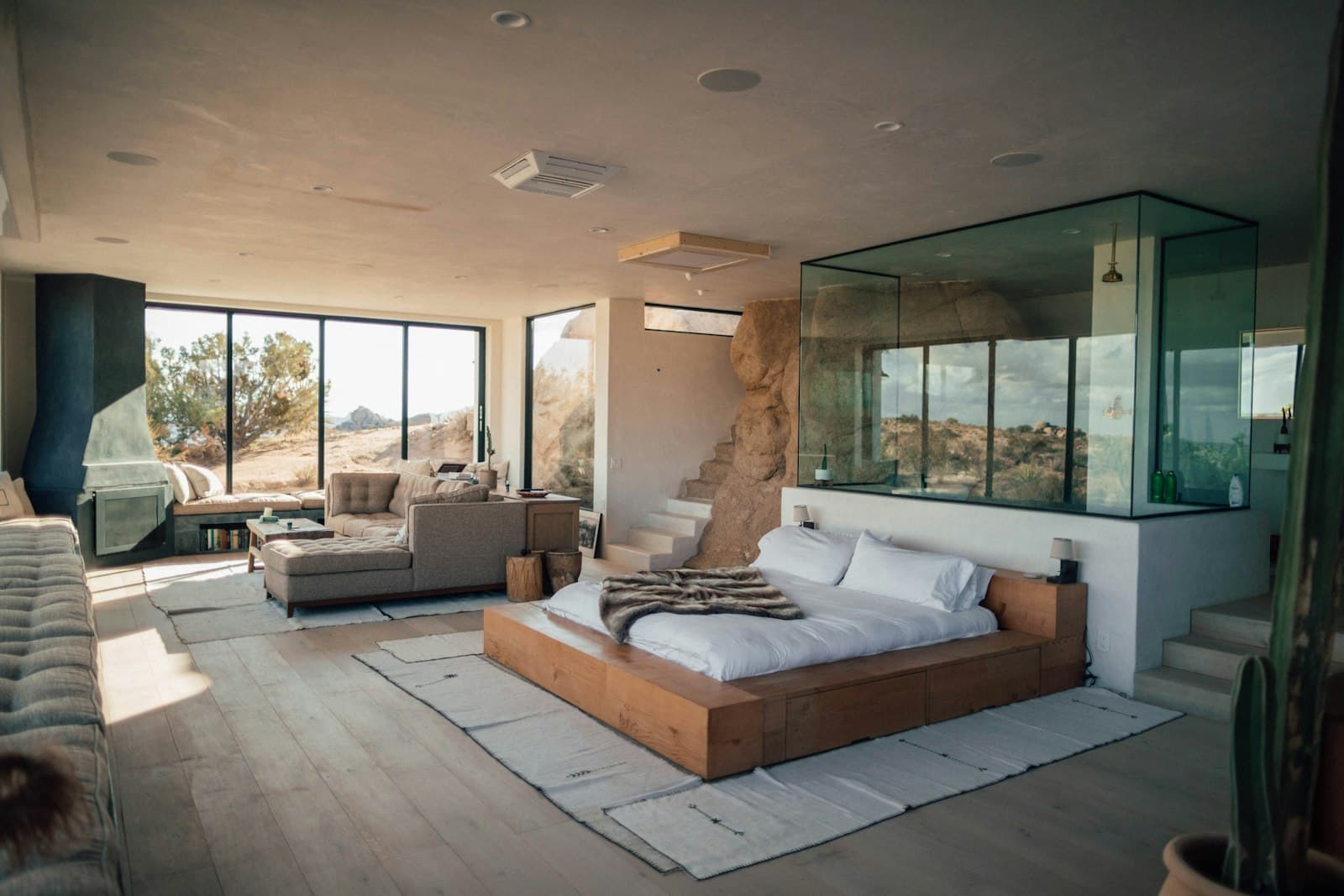 A bright, minimally furnished suite with a bed facing tall windows
