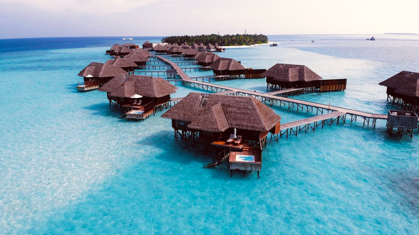 Timber overwater bungalows glowing above a still lagoon at dusk