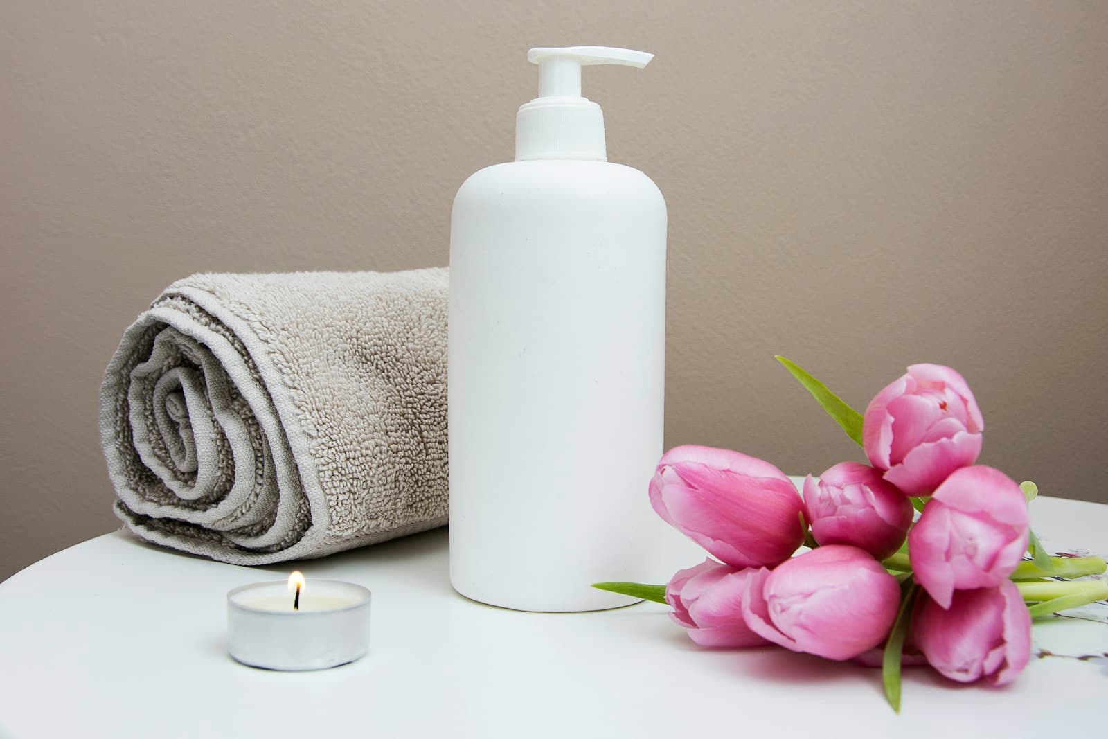 Folded towels, tea lights and fresh blooms arranged on a spa counter