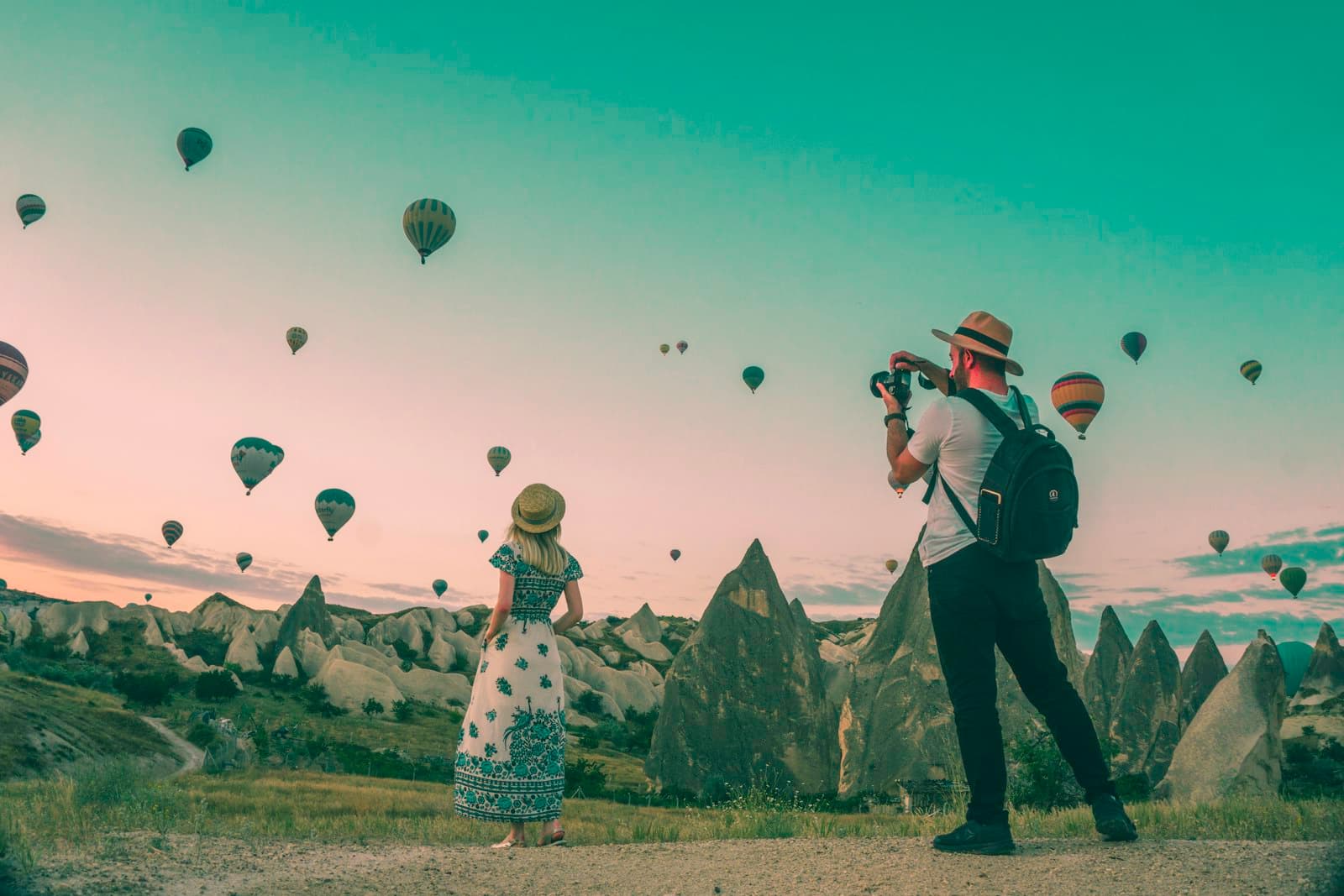 Hot air balloons drifting over a valley in the first light of morning